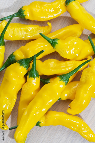 Close-up of yellow lemon drop chillis on a light wooden table photo