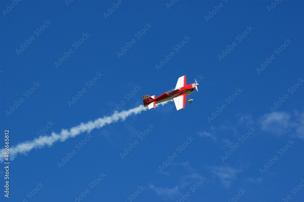 Model of acrobatic airplane flying in a blue sky - obrazy, fototapety, plakaty 
