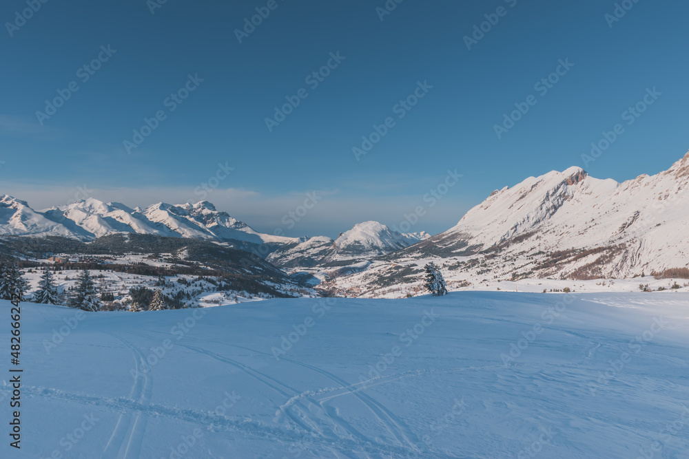 A picturesque landscape view of the French Alps mountains with ski traces in the fresh snow on a cold winter day (Hautes-Alpes, Devoluy valley)