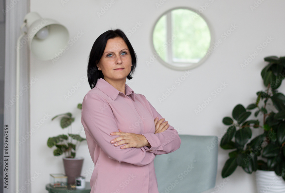 Pretty dark haired woman. 40 years. Standing in the room and looking at the camera. Portrait. Selective focus. High quality photo. copyspace 