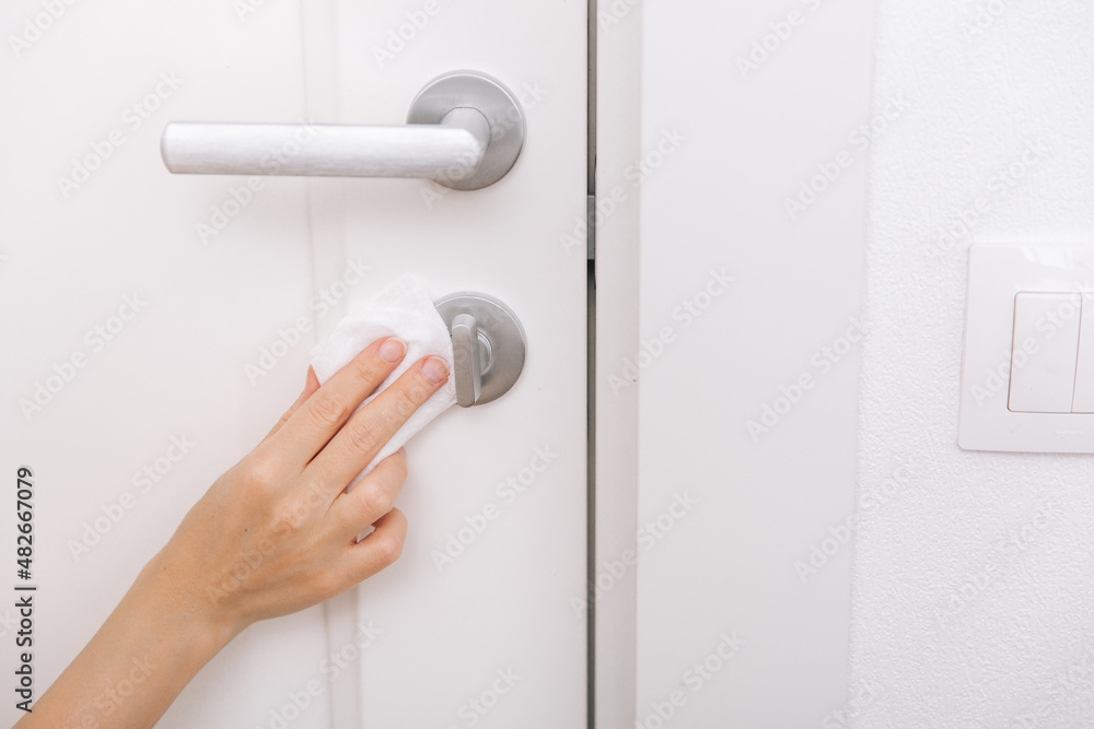 Cleaning door handles with an antiseptic wet wipe and gloves. Sanitize surfaces prevention in hospital and public spaces against corona virus. Woman hand using towel for cleaning home room door link Cleaning door handles with an antiseptic wet wipe and gloves. Sanitize surfaces prevention in hospital and public spaces against corona virus. Woman hand using towel for cleaning home room door link