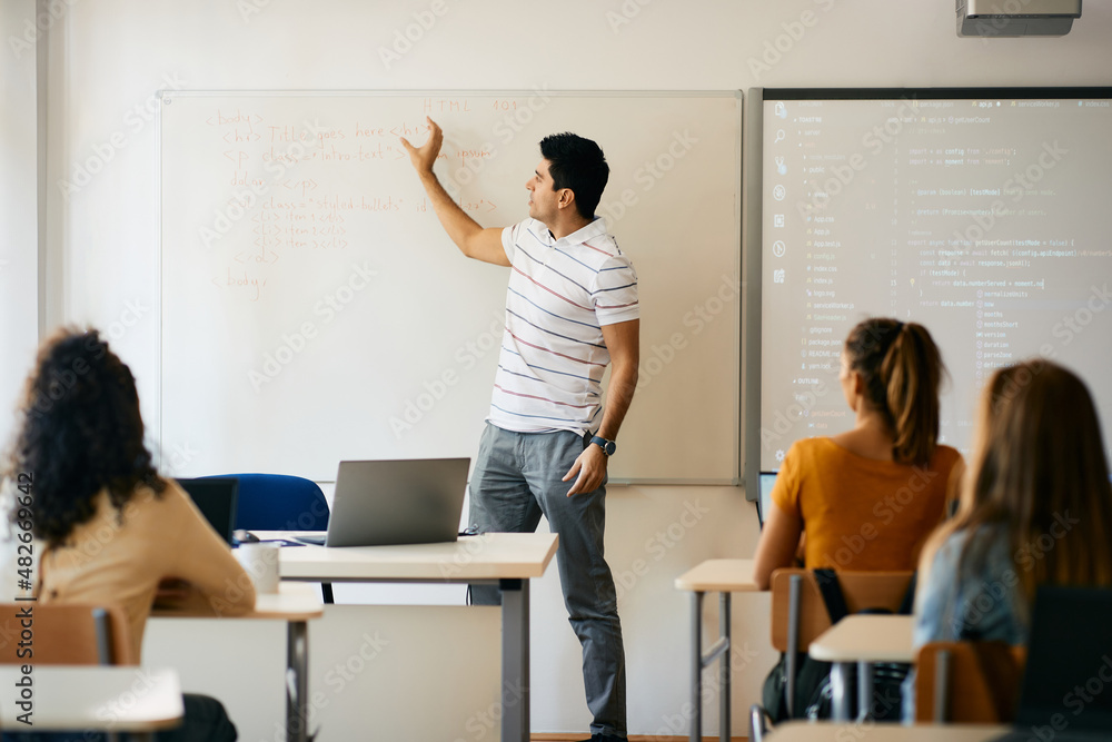 Male professor giving lecture during IT class in the classroom at high school. Male professor giving lecture during IT class in the classroom at high school.