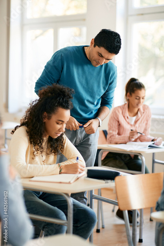 High school teacher assisting black female student during a class in the classroom.