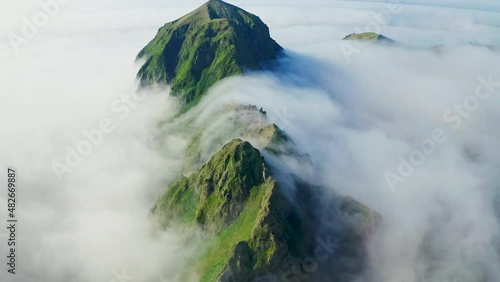 Magic aerial panorama. High green mountain range covered with dense white clouds