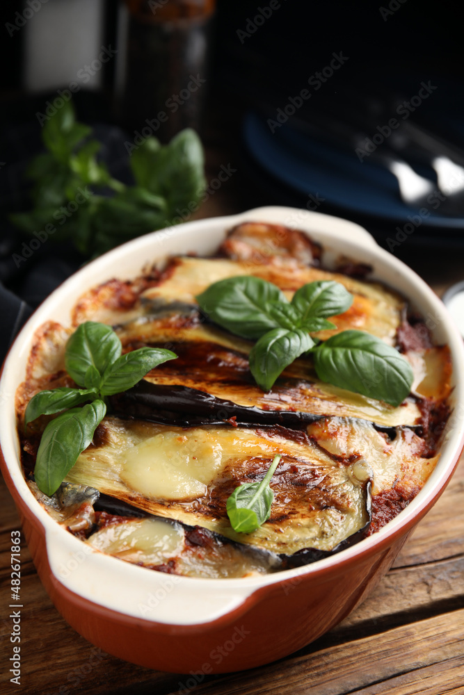 Delicious eggplant lasagna in baking dish on wooden table