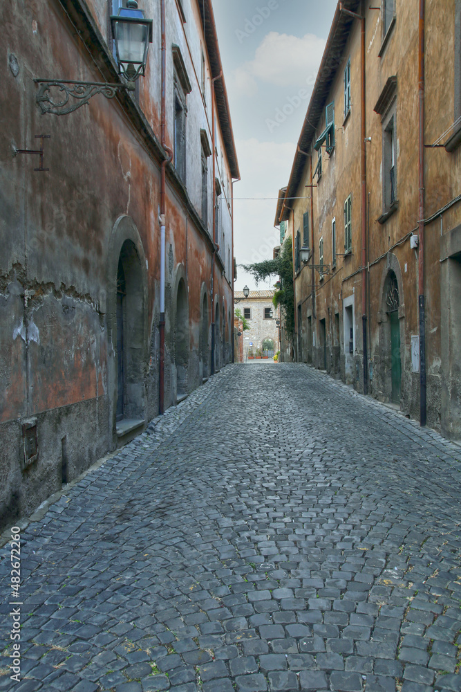 A narrow paved urban street, between typical old stone buildings, Tuscania, Tuscia, Lazio, Italy