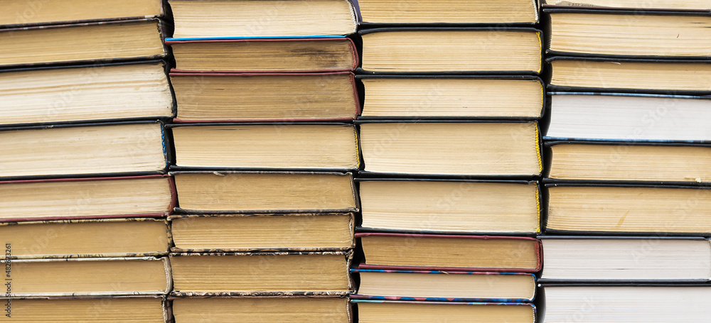 Books stack on wooden table and blurred bookshelf in library hall. Books stack on wooden table and blurred bookshelf in library hall.
