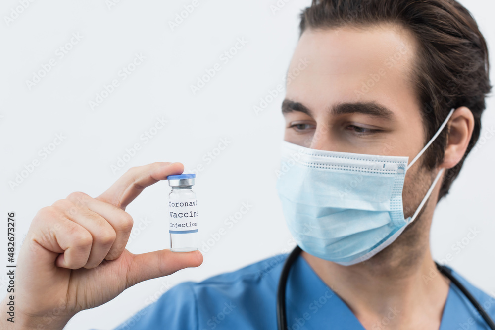 blurred doctor in medical mask holding coronavirus vaccine isolated on grey. blurred doctor in medical mask holding coronavirus vaccine isolated on grey.
