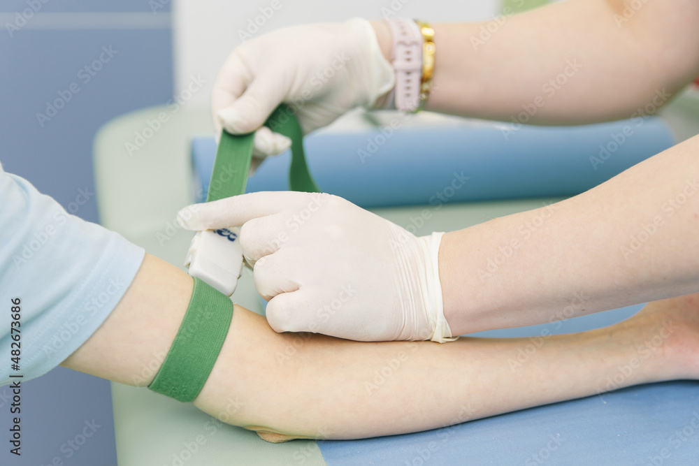 Taking a blood test from a vein in the treatment room. Nurse pricking a syringe with a needle into the patient hand. Swab pressed against the injection site during blood donation. Tube with blood Taking a blood test from a vein in the treatment room. Nurse pricking a syringe with a needle into the patient hand. Swab pressed against the injection site during blood donation. Tube with blood