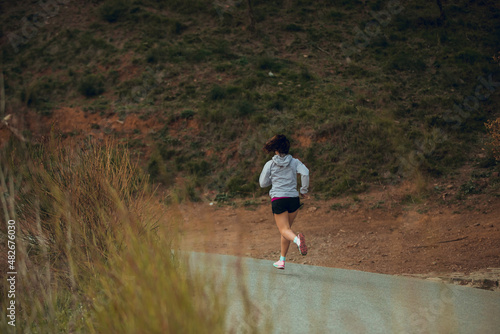 Girl running on asphalt near a forest © Aitor