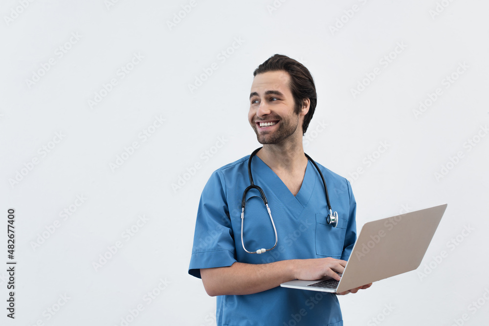 smiling physician with laptop looking away isolated on grey. smiling physician with laptop looking away isolated on grey.