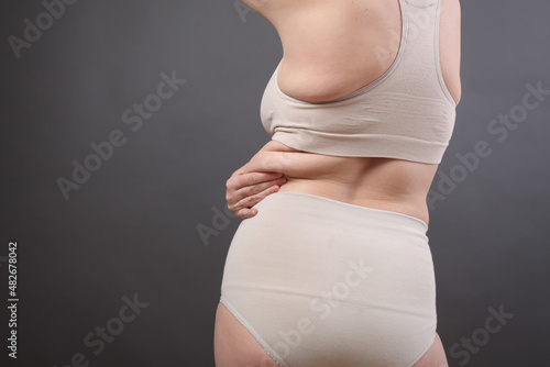 Fotografie excess weight on the belly in the hands of a young woman after giving birth