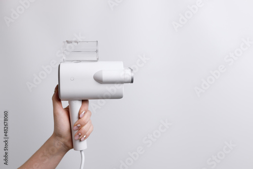 clothes steamer in hands on a gray background