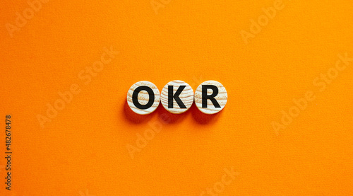 OKR, objectives and key results symbol. Concept words OKR objectives and key results on wooden circles on a beautiful orange background. Business OKR objectives and key results concept. Copy space. photo