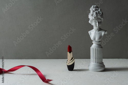 Red lipstick on a light textured background, plaster figure.Сopy space.