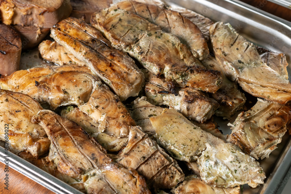 Sturgeon steaks baked on charcoal, laid out on a baking sheet. Iron pan with fish, blanks for catering. Sturgeon steaks baked on charcoal, laid out on a baking sheet. Iron pan with fish, blanks for catering.