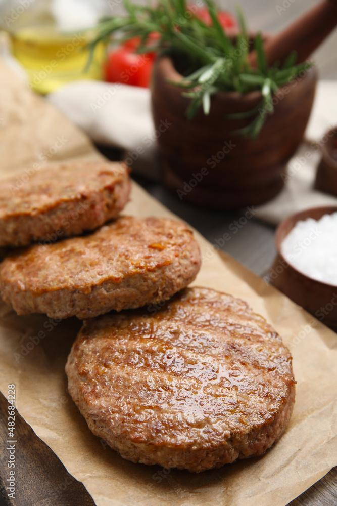 Serving board with tasty grilled hamburger patties on wooden table, closeup