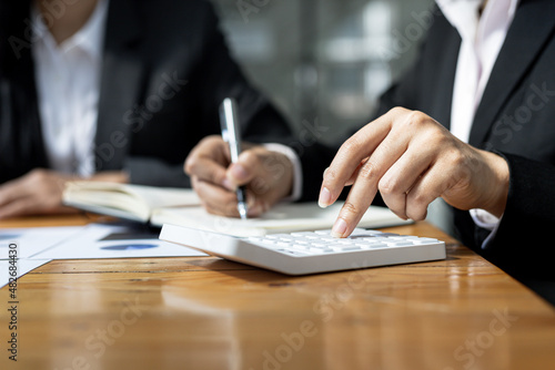 Close-up view A businessman using a calculator to calculate numbers on a company's financial documents, he is analyzing historical financial data to plan how to grow the company. Financial concept.