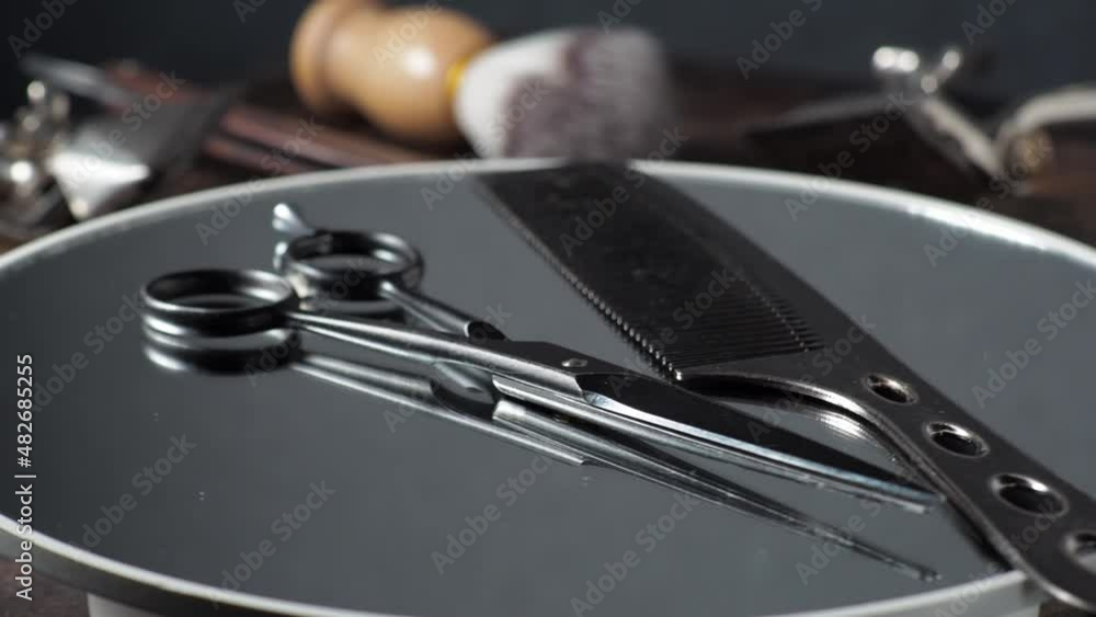 Hairdressing scissors and comb rotate on the mirror. Barber tools in the background. 4k Hairdressing scissors and comb rotate on the mirror. Barber tools in the background. 4k