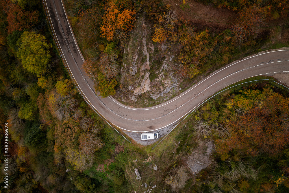 Drone view of a camper van with solar panels on a road on a mountain landscape during Autumn