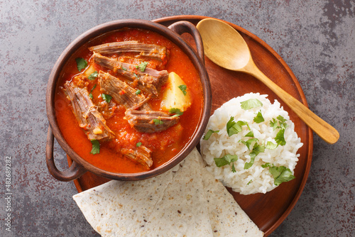 Hilachas traditional dish of Guatemalan cuisine, rice, potatoes, tomato sauce, and tortillas closeup in the plate on the table. Horizontal top view from above photo