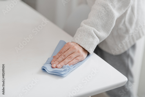 Cleaning the table with a blue microfiber cloth. Sanitize surfaces prevention in hospital and public spaces against coronavirus. Woman hand using wet wipe at home. Cleaning the room