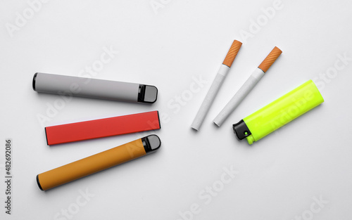 Lighter, electronic and regular cigarettes on white background, top view