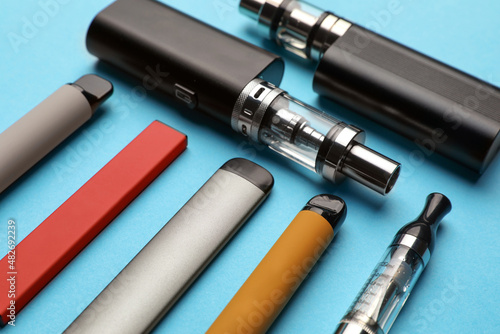 Foto Different electronic cigarettes on light blue background, closeup