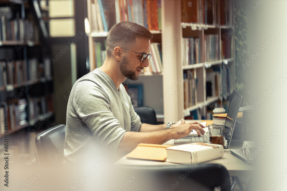 Male student studying in the campus library .
Male student studying in the campus library .