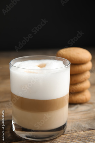 Delicious latte macchiato and cookies on wooden table