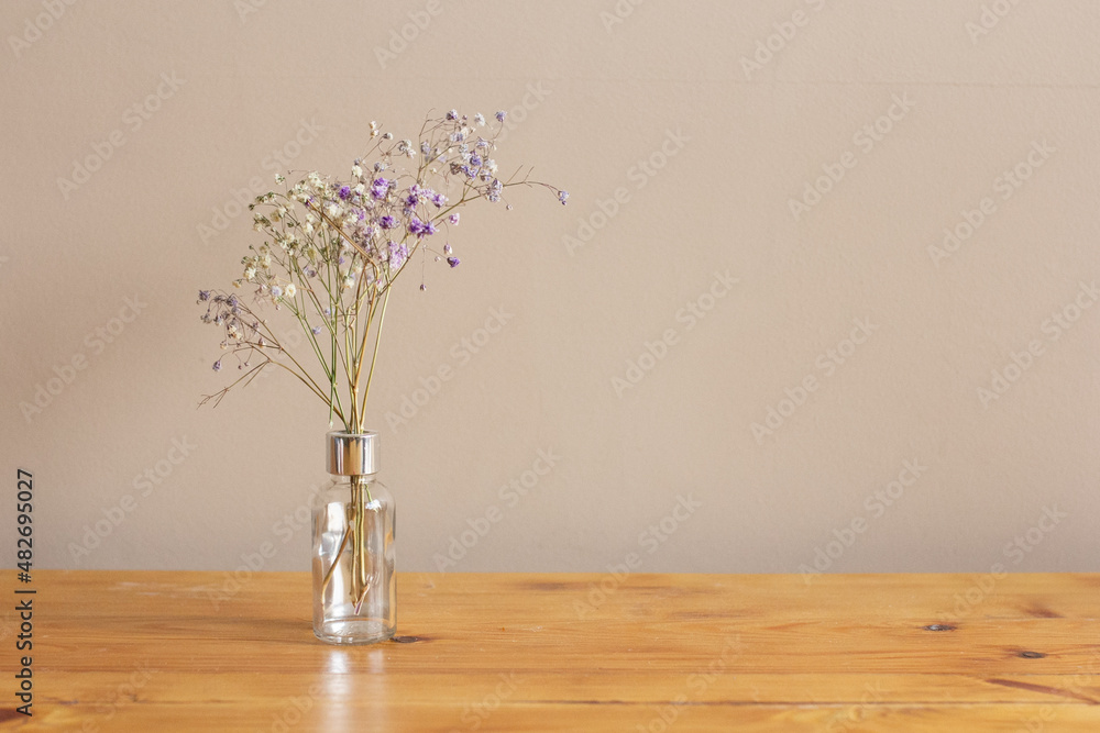 Fragile flowers in vase on wooden table