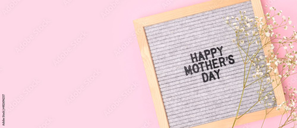 Naklejka premium Happy Mothers day. Banner with letter board and gypsophila flower on a pink background. Festive concept.