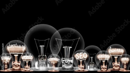 Group of light bulbs in a row going from dark to light with Digital Marketing, Brand, SEO, Business, Advertising and Strategy fiber text on black background. High quality 4k video.