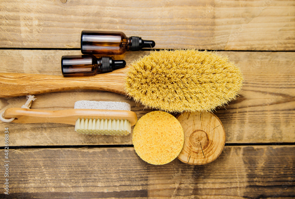 Wooden brush for dry body massage,sponge, jars of oil. Anti-cellulite brush for body massage on a wooden background.
