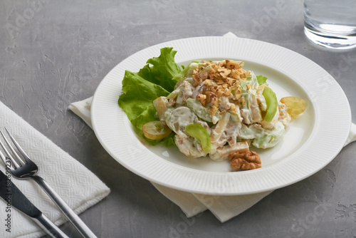 classic american waldorf salad made of apples celery walnuts grapes mayonnaise whipped cream white plate grey background
