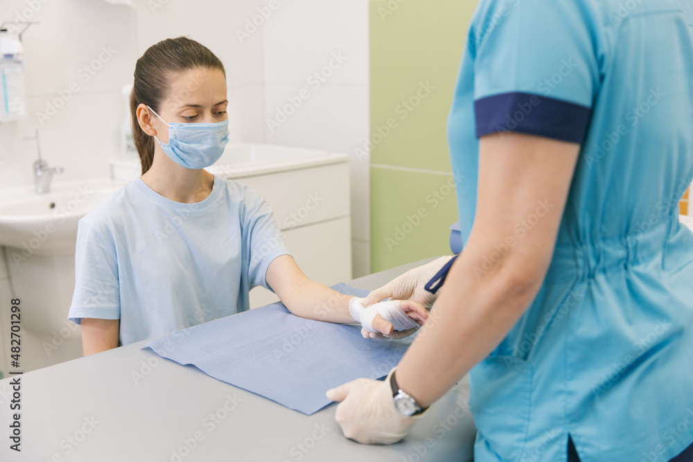 Obraz premium A doctor wrapped around the wrist for first aid close-up. Application of bandages on the patient's hands, first aid concepts and wrist injury treatment. Medical bandage on patient hand. Wrist pain.