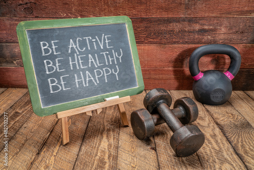 Fototapeta Naklejka Na Ścianę i Meble -  Be active, be healthy, be happy   inspirational concept -  white chalk text on a slate blackboard sign against weathered rustic wood with a dumbbells and kettlebell