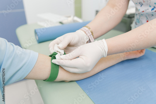 Taking a blood test from a vein in the treatment room. Nurse pricking a syringe with a needle into the patient hand. Swab pressed against the injection site during blood donation. Tube with blood.