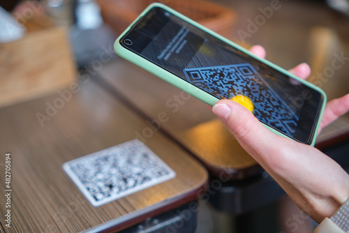 Obraz na plátne Closeup of guest hand ordering meal in restaurant while scanning qr code with mo