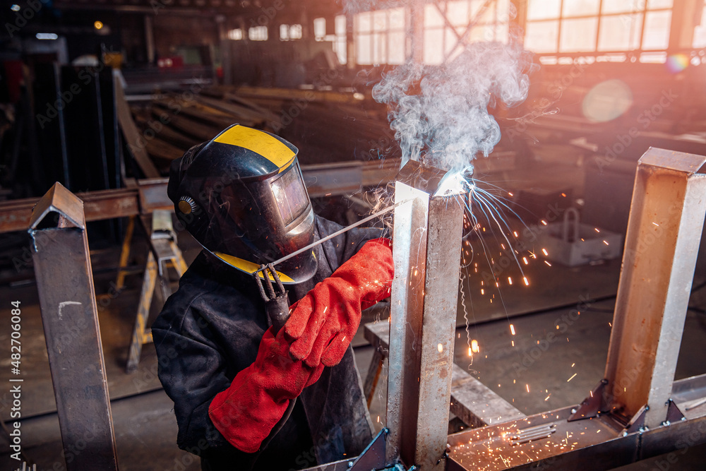 Factory industrial weld worker in workplace with spark. Professional welder erecting metal steel Factory industrial weld worker in workplace with spark. Professional welder erecting metal steel