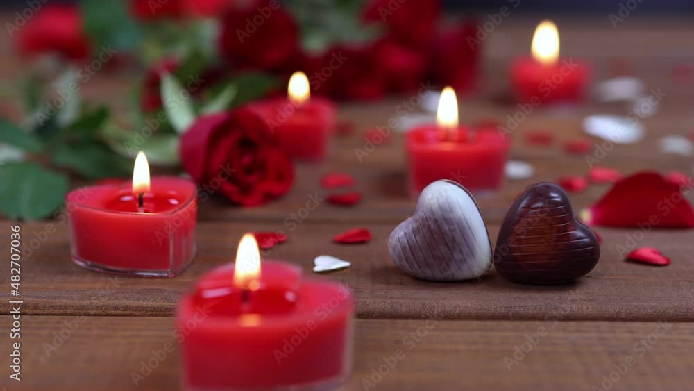 Valentines Day concept chocolate candies heart shaped and red roses with candles on wood. Love and romance concept. Dolly shot 4k Valentines Day concept chocolate candies heart shaped and red roses with candles on wood. Love and romance concept. Dolly shot 4k