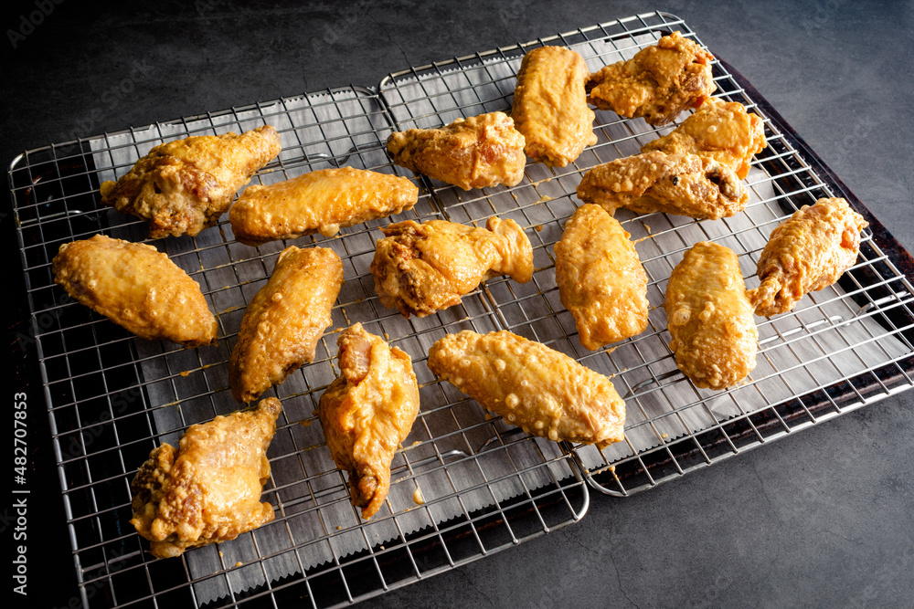 Uncooked Marinated Chicken Wings Dusted in Baking Powder: Raw chicken wings arranged on a wire rack on a sheet pan Uncooked Marinated Chicken Wings Dusted in Baking Powder: Raw chicken wings arranged on a wire rack on a sheet pan
