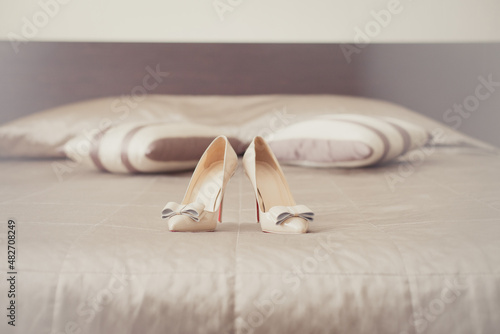 Bride's wedding shoes on a bed in a bedroom. Bride's morning. Wedding accessories in beige colors. Preparation to wedding day. Elegant female footwear