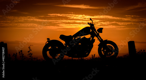 A silhouette of a custom made chopper against a colourful sunset in England  UK