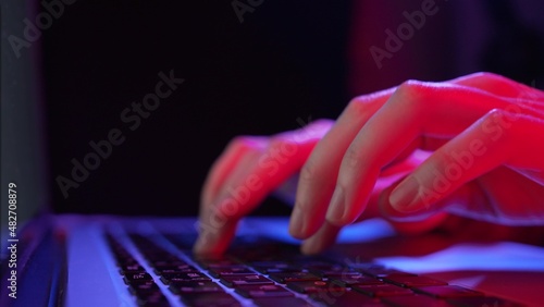 фотографія Young woman hands type on keyboard buttons of laptop working distantly at neon p