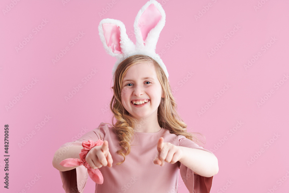 Portrait of happy child in dress pointing in camera on pink