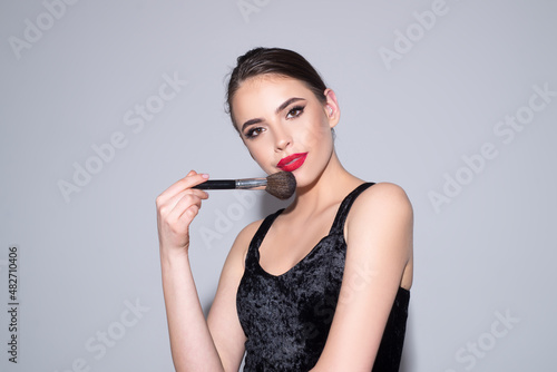 Beautiful brunette young woman applying powder on her cheeks with a cosmetic brush. Beauty woman with clean healthy skin, natural make up, spa concept. Beautiful tender girl.