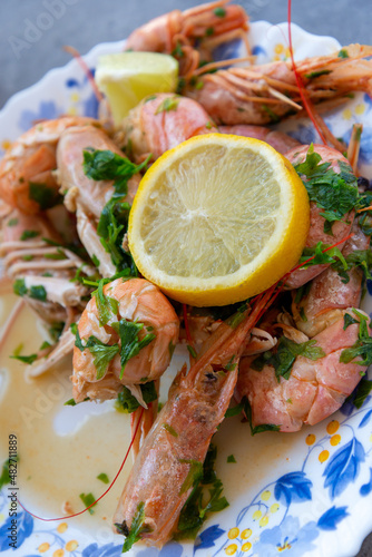 Fresh shrimp and langoustines on a plate served with green parsley and a slice of lemon. Mediterranean cuisine