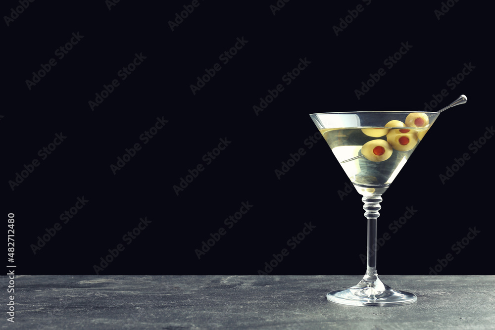 Martini cocktail with olives on grey table against dark background, space for text Martini cocktail with olives on grey table against dark background, space for text