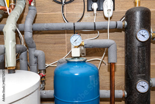 Expansion vessel to protect against overpressure and a hydraulic clutch in a modern natural gas boiler room, lined with ceramic tiles. photo